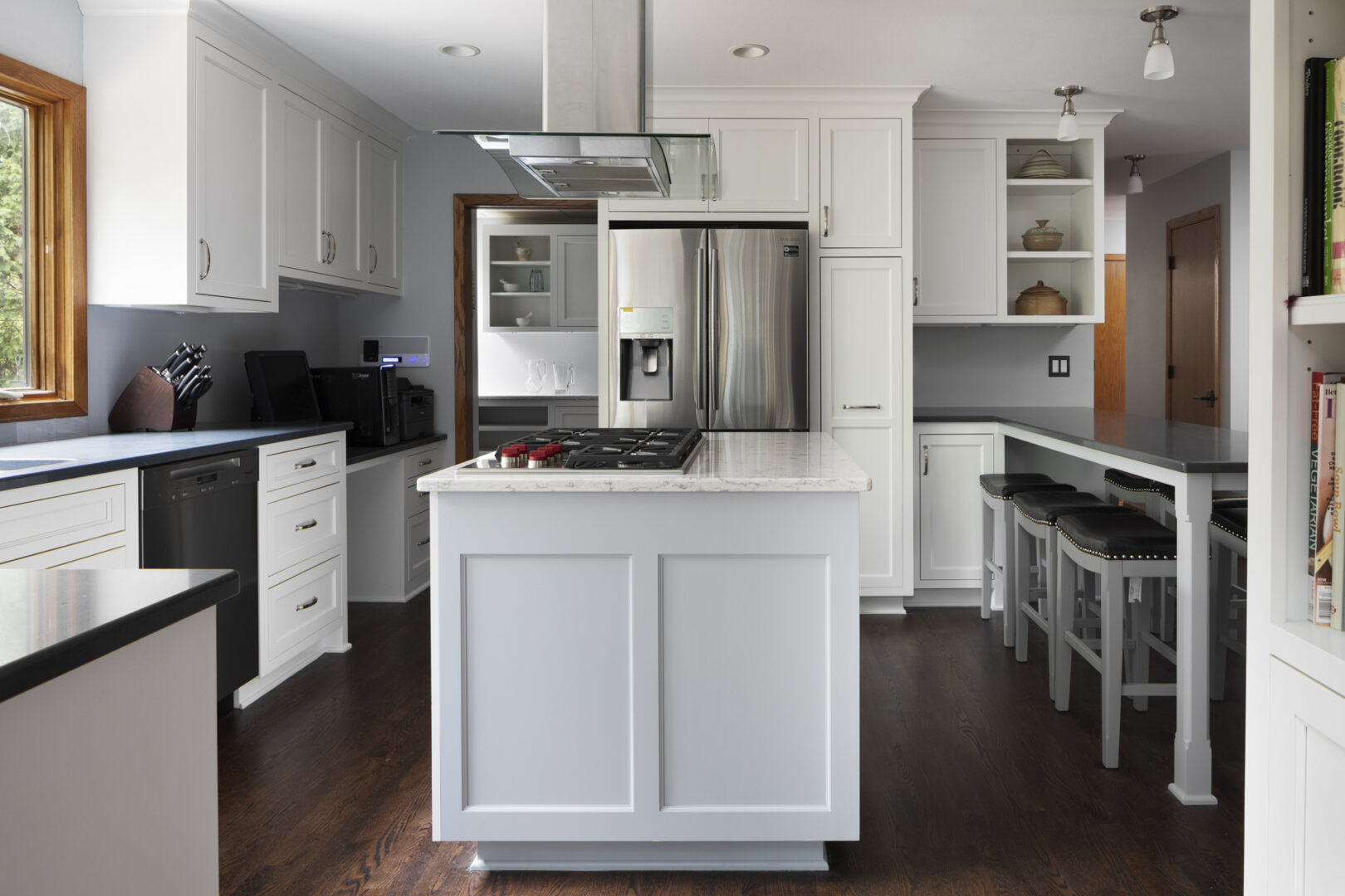 a white kitchen with wooden flooring and a metallic refrigerator