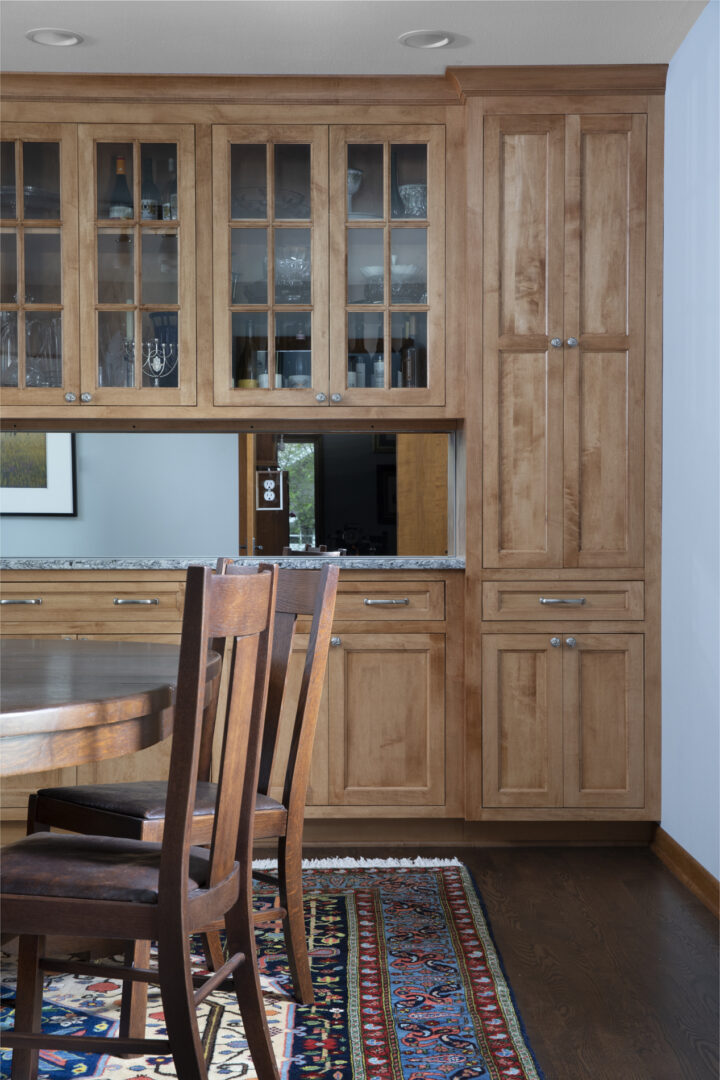 a room with wooden cupboards, chairs, and a table